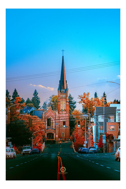 Street leading to a brick church at dusk among autumn trees