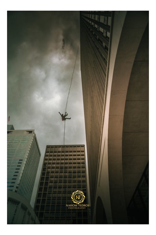 Highliner crossing between skyscrapers under a cloudy sky